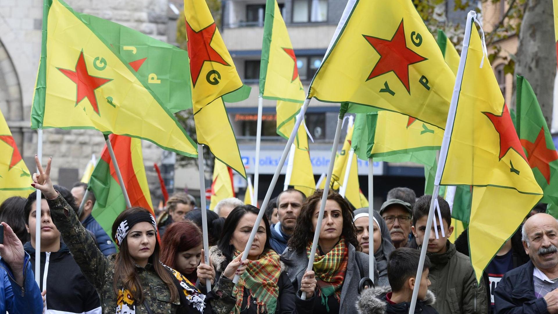 Demonstranten halten YPG-Fahnen bei einer Demonstration von Kurden gegen die türkische Militär-Offensive in Nordsyrien in Köln am 19.10.2019.