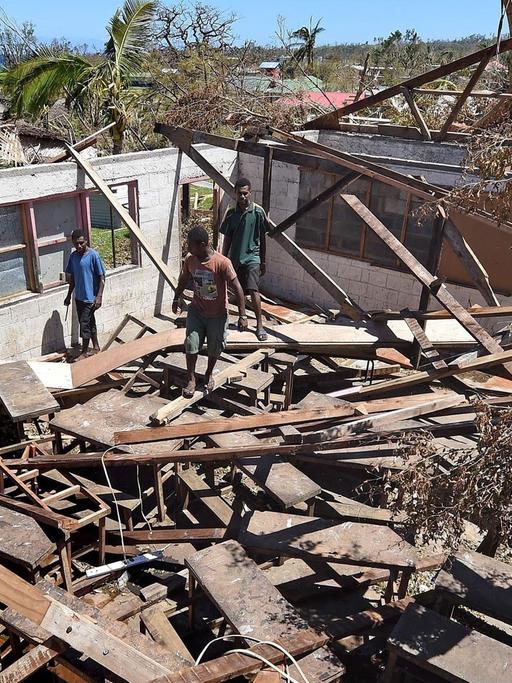 Menschen stehen in einem zerstörten Haus in Vanuatu.