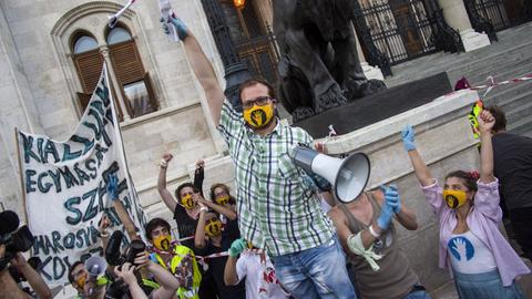 Proteste von Studenten: Einer hält ein Mikrofon. Alle tragen gelbe Masken.