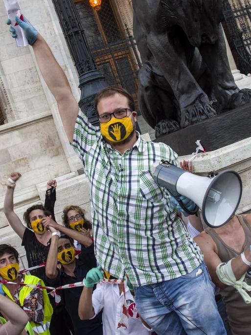 Proteste von Studenten: Einer hält ein Mikrofon. Alle tragen gelbe Masken.