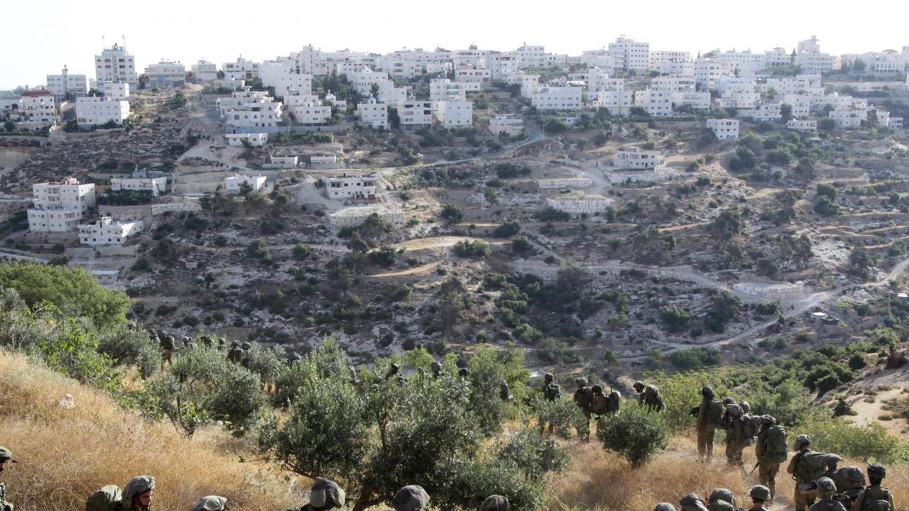 Blick aus der Ferne auf Hebron. Am unteren Bildrand sieht man zahlreiche israelische Soldaten im Gänsemarsch. Blick aus der Ferne auf Hebron. Am unteren Bildrand sieht man zahlreiche israelische Soldaten im Gänsemarsch.