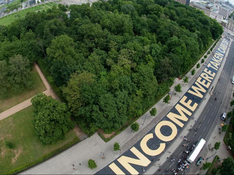 "INCOME WERE TAKEN CARE" steht am 29.05.2016 auf der Straße des 17. Juni zwischen der Siegessäule und dem Brandenburger Tor in Berlin in großen Letter geschrieben. Der Satzteil gehört zur Frage "WHAT WOULD YOU DO IF YOUR INCOME WERE TAKEN CARE OF?".