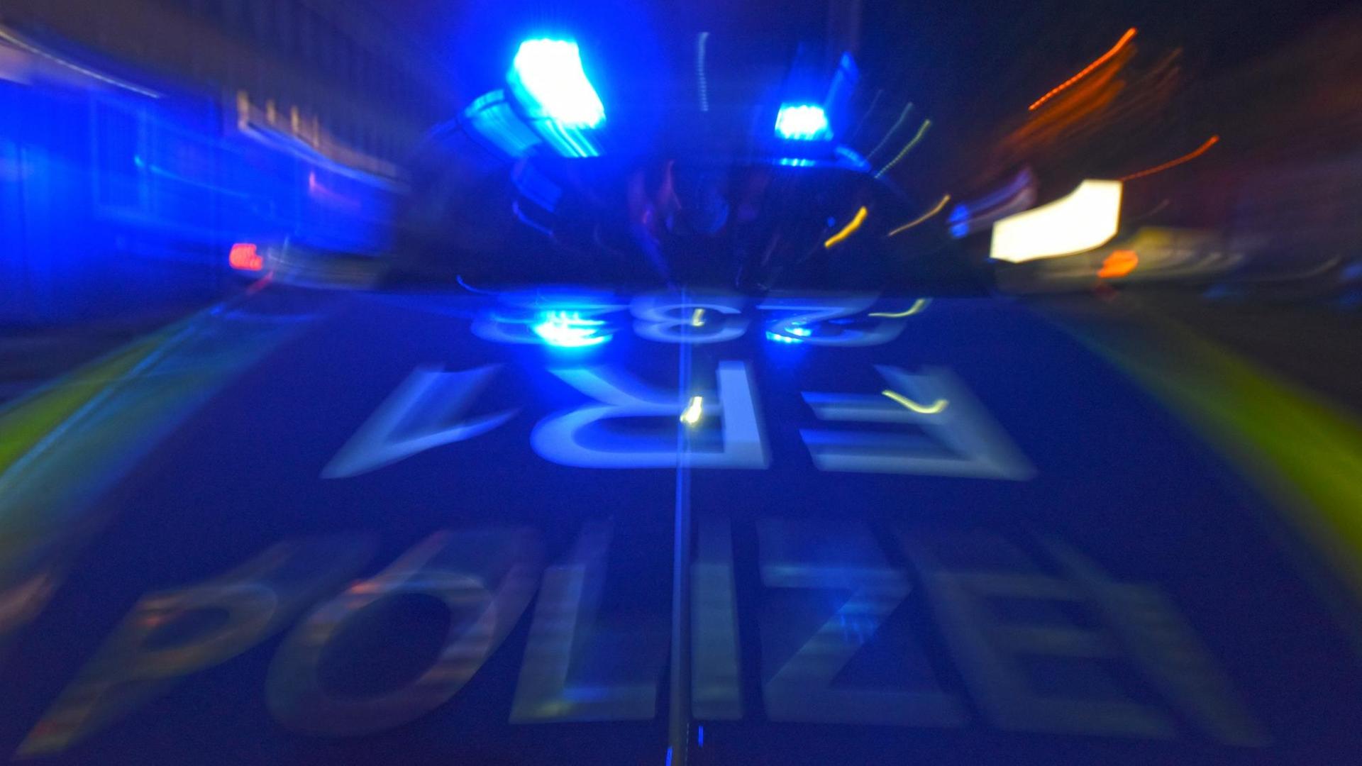 Das Foto zeigt verschwommen ein Polizeifahrzeug mit Blaulicht.