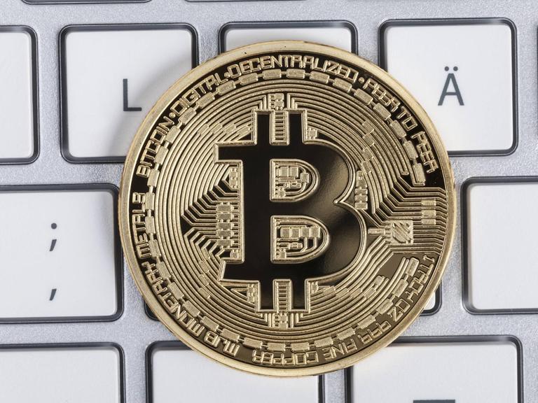 Ein Münze mit der Aufschrift Bitcoin liegt auf einer Tastatur. In Erscheinung getreten ist die Blockchain-Technik erstmals mit der rein digitalen Währung Bitcoin, jetzt soll sie auch für andere Zwecke eingesetzt werden.