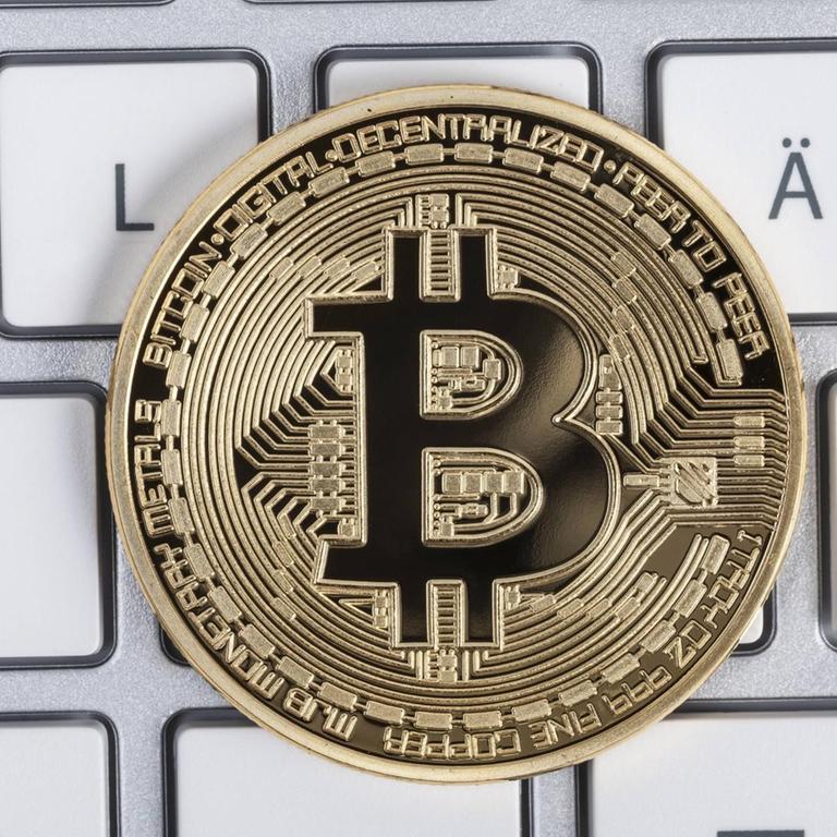 Ein Münze mit der Aufschrift Bitcoin liegt auf einer Tastatur. In Erscheinung getreten ist die Blockchain-Technik erstmals mit der rein digitalen Währung Bitcoin, jetzt soll sie auch für andere Zwecke eingesetzt werden.

