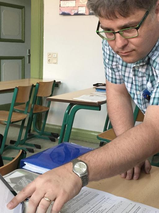 Mathelehrer Horst Kretschmer zeigt zwei Schülerinnen etwas auf dem Tablet.