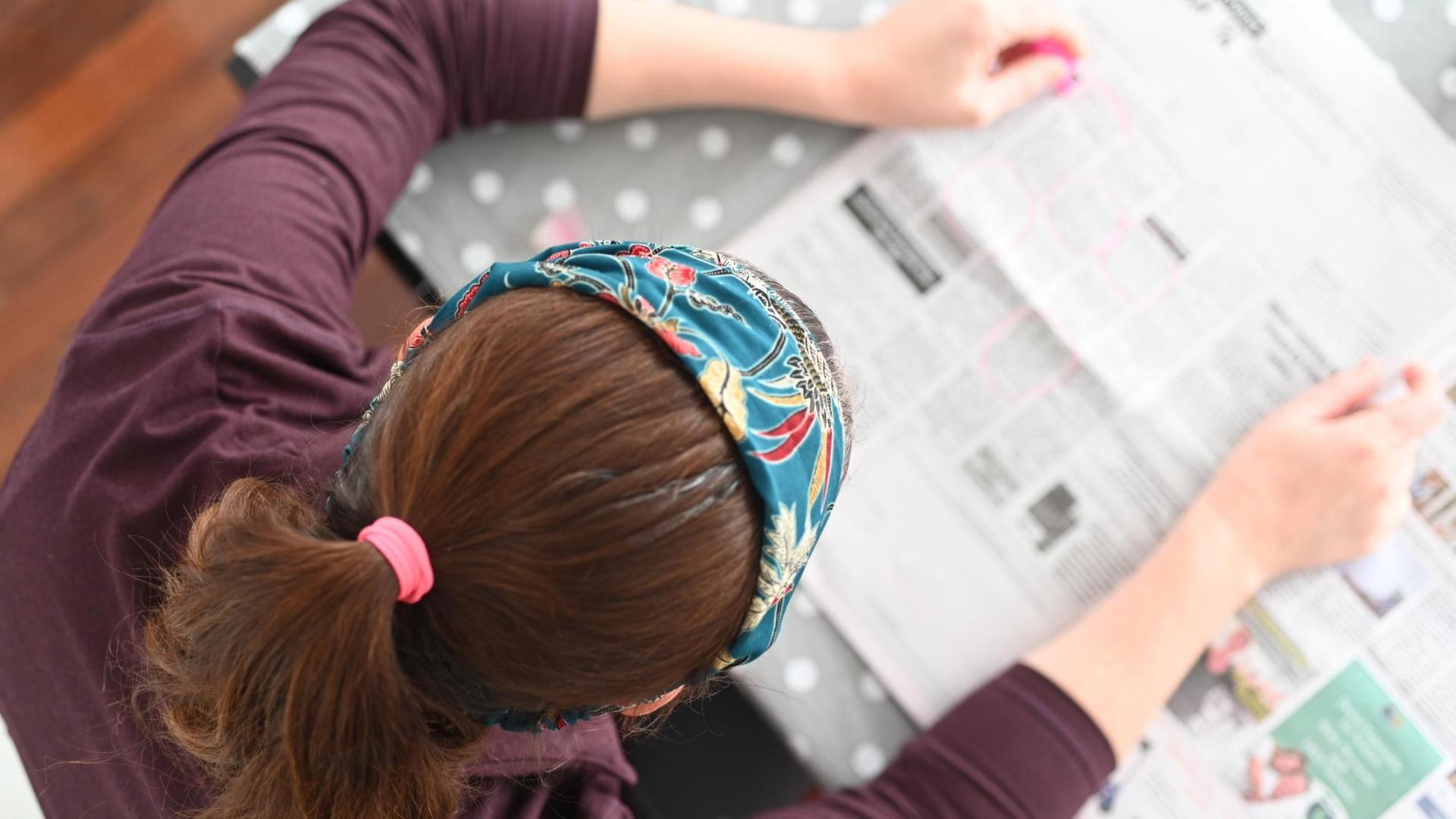Eine Frau liest in einer Zeitung, sie ist von oben zu sehen.