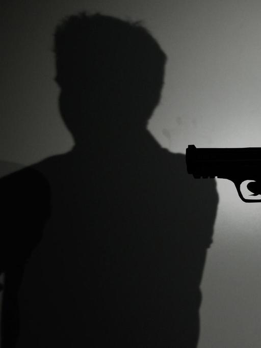 Eine Frau hält ein Modell einer Waffe (Silhouette).