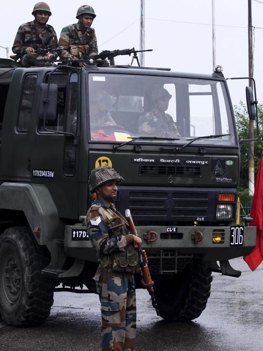 Bewaffnete Soldaten stehen bei einem Armee-Laster auf einer Straße