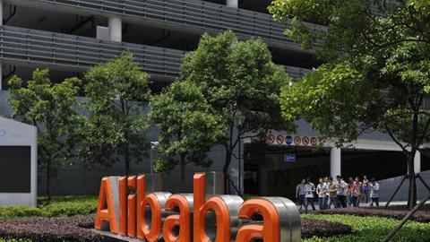 Chinesische Arbeiter verlassen das Alibaba-Hauptquartier im Osten Chinas, vor dem der Alibaba-Schriftzug zu sehen ist.