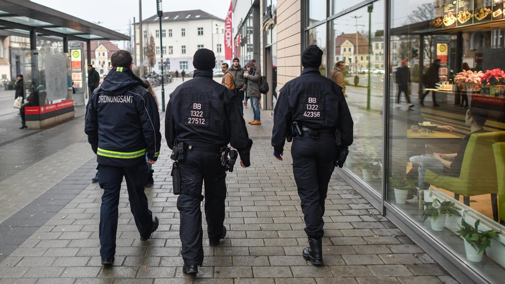 Ein Mitarbeiter des Ordnungsamtes und zwei Beamte der Bereitschaftspolizei gehen auf Streife in Cottbus.