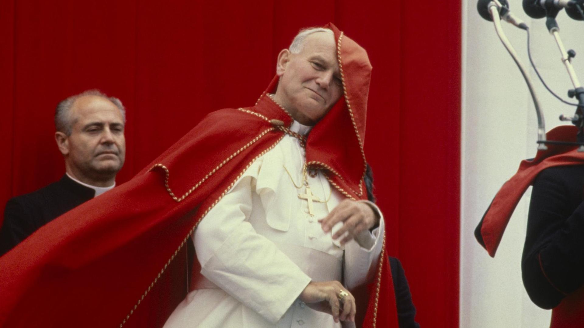 Johannes Paul II. mit wehendem roten Umhang im päpstlichen Ornat.