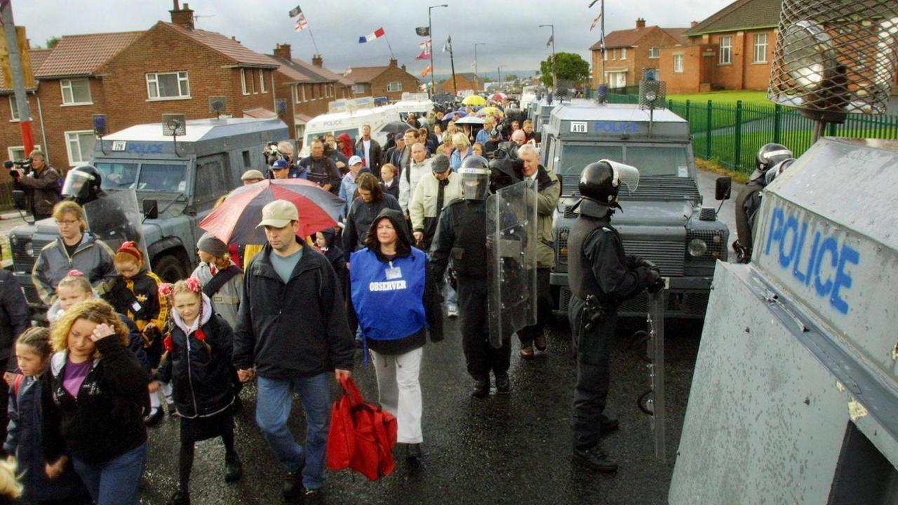 Geschützt von Polizisten gehen katholische Familien mit ihren Schulmädchen am 7.9.2001 durch ein protestantisches Viertel zu der katholischen Holy Cross-Schule in Belfast.