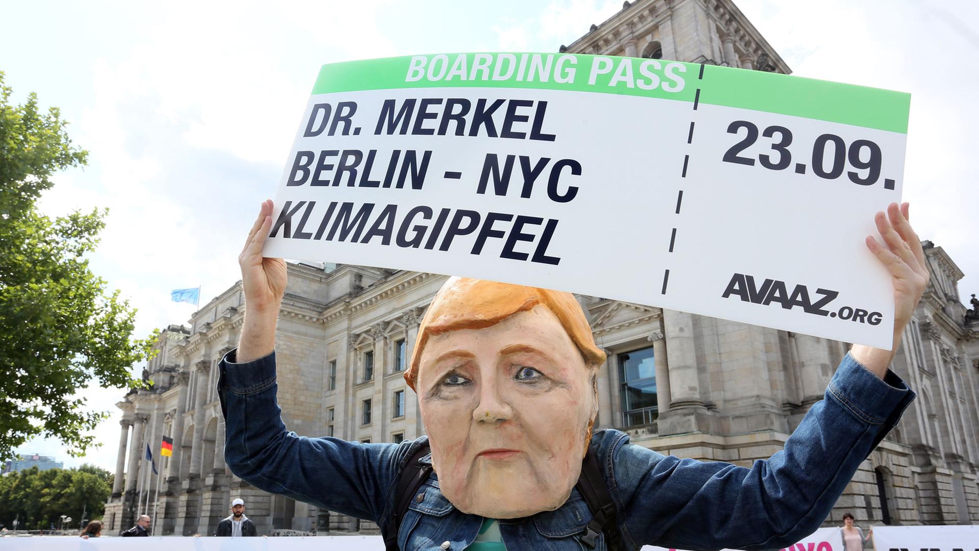 Als Bundeskanzlerin Merkel verkleidet hält ein Demonstrant am 24.08.2014 einen symbolischen Boardingpass in den Händen, der für die Teilnahme Merkels am Klimagipfel in New York stehen soll.