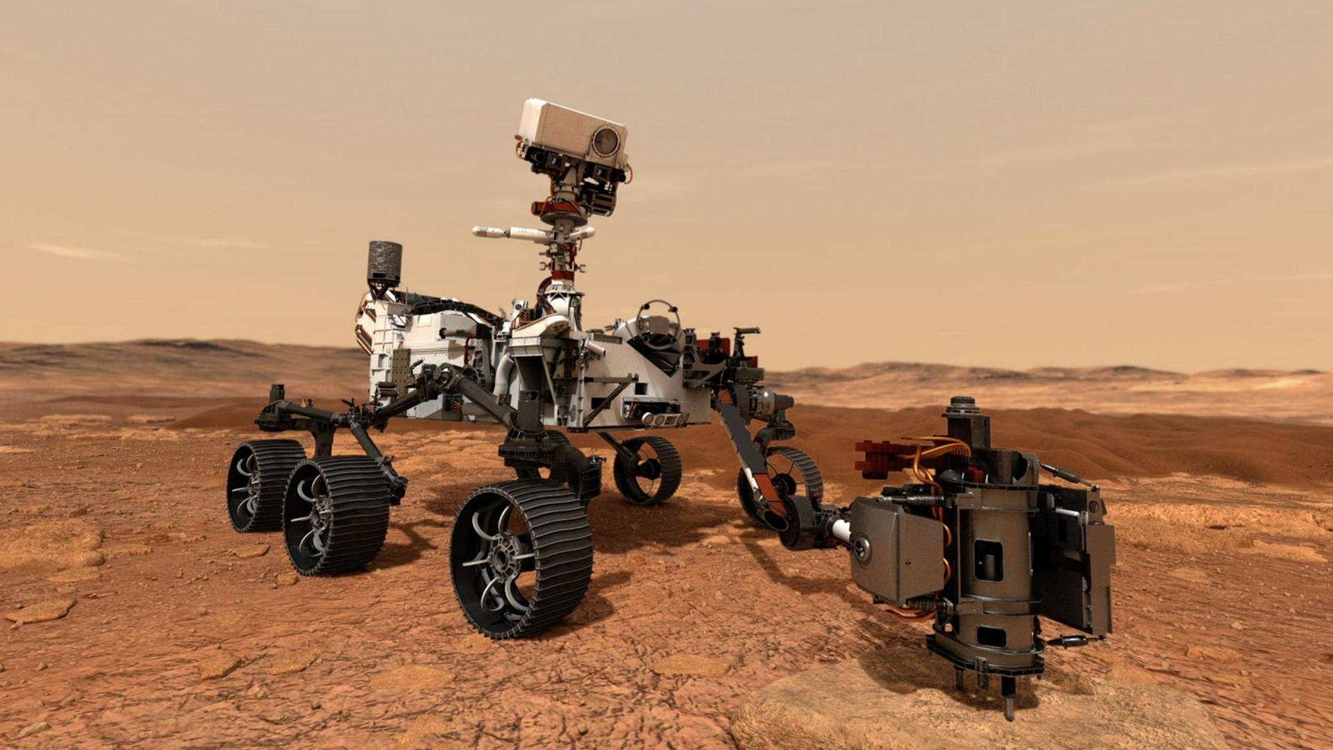 Der Mars-Rover "Perseverance" steht auf dem roten Gestein auf dem Planeten Mars. Er sieht aus wie eine Art Gelände-Wagen mit sechs Rädern.