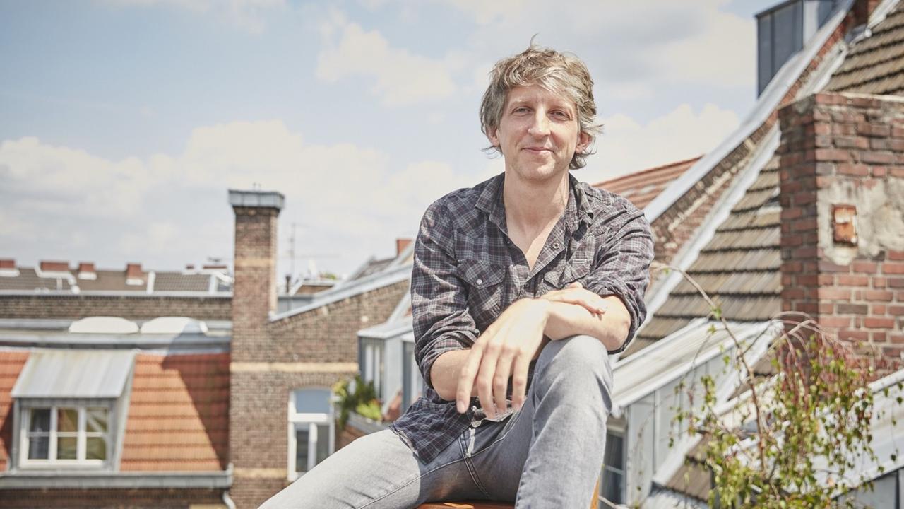 Der Musiker William Wahl sitzt auf einem Dach