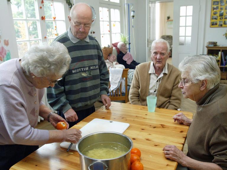 Senioren einer Wohngemeinschaft bei der Zubereitung des Mittagessens