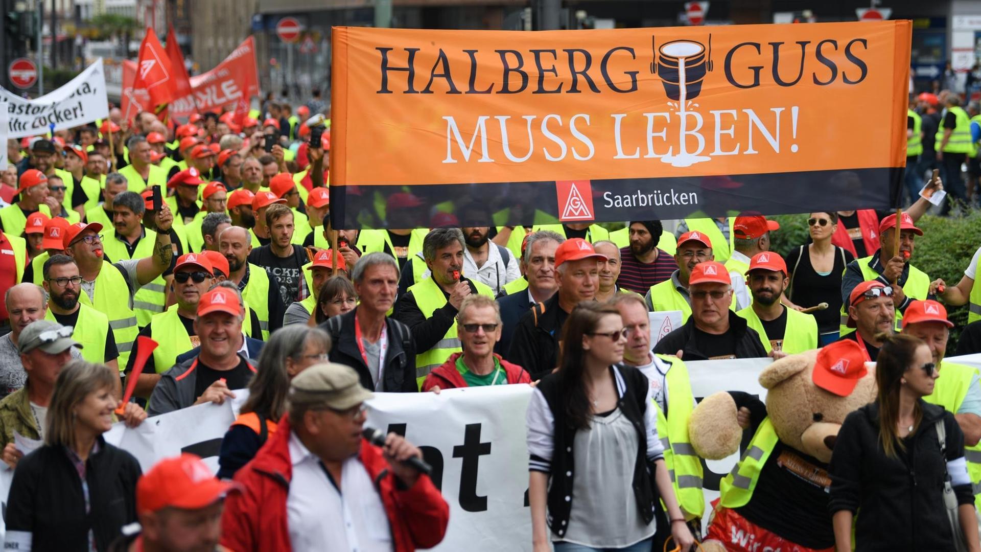 Beschäftigte des Autozulieferers Neue Halberg Guss (NHG) ziehen während einer Demonstration mit einem Transparent mit der Aufschrift "Halberg Guss muss leben" durch das Frankfurter Bahnhofsviertel.