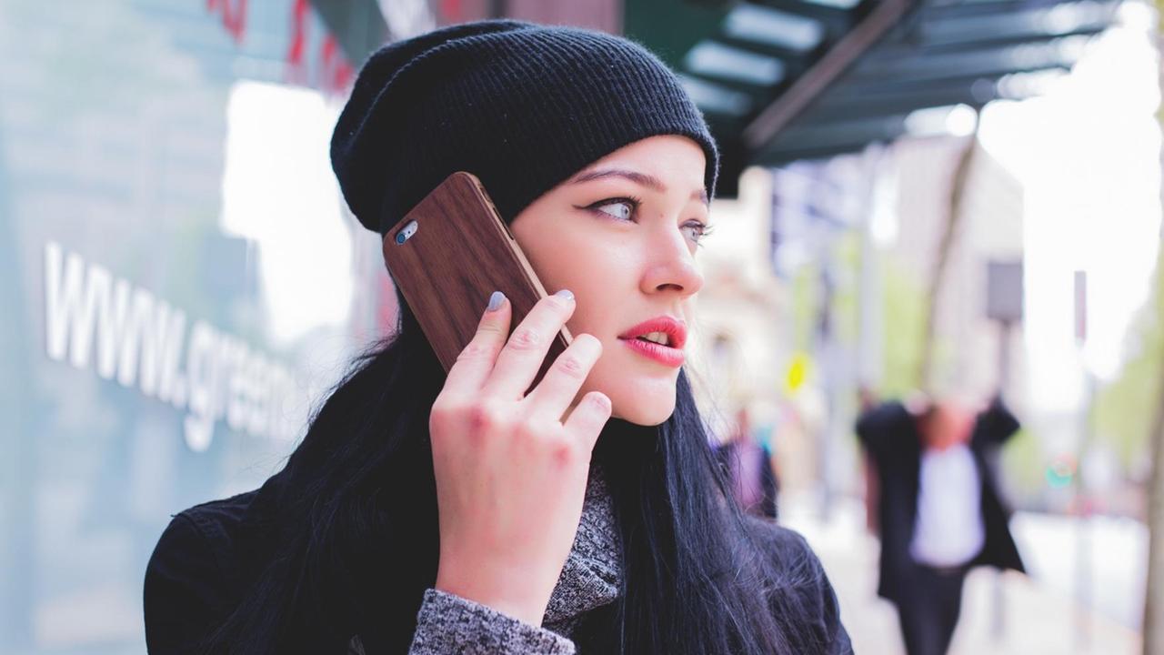 Eine junge Frau mit Wollmütze telefoniert mit ihrem Smartphone.