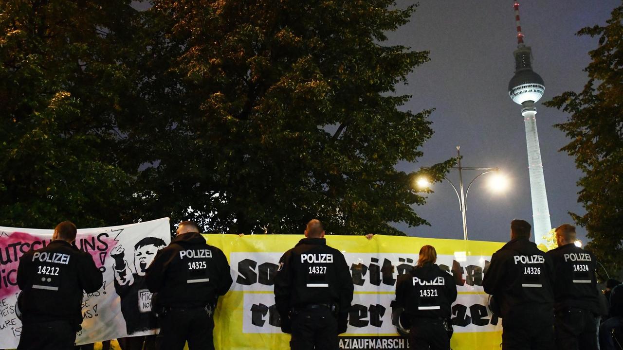 Polizisten stehen am 24.09.2017 in Berlin vor Demonstranten, die gegen die Partei Alternative für Deutschland (AfD) demonstrieren. Im Hintergrund ist der Fernsehturm zu sehen.
