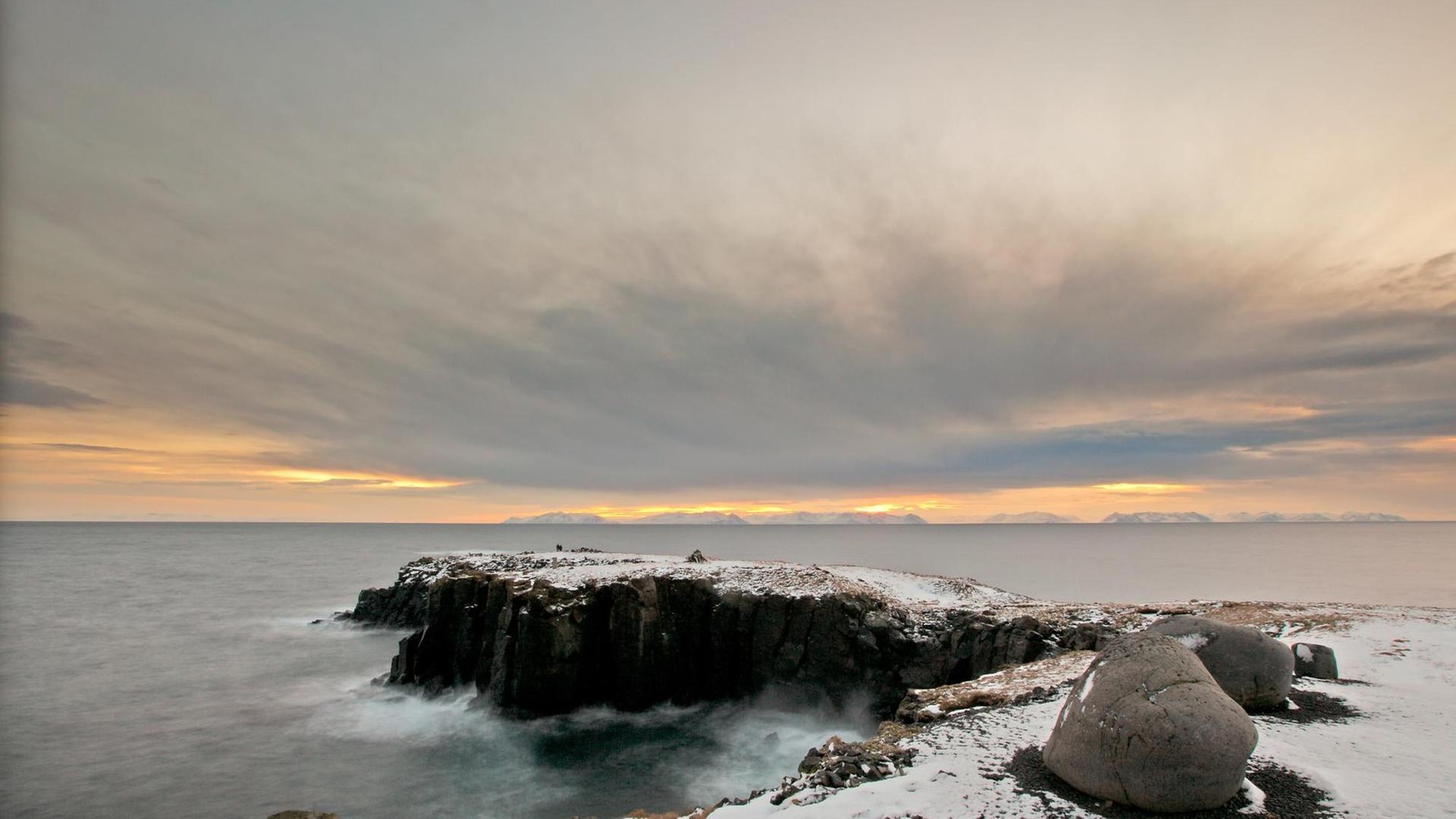 Landzunge mit Steilküste auf dem isländischen Eiland Grimsey im Sonnenuntergang Landzunge mit Steilküste auf dem isländischen Eiland Grimsey im Sonnenuntergang