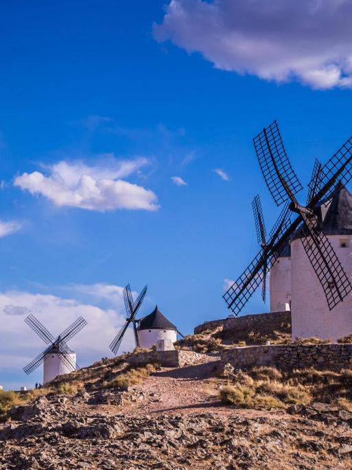 Mehrere Windmühlen stehen in einer Landschaft in Spanien