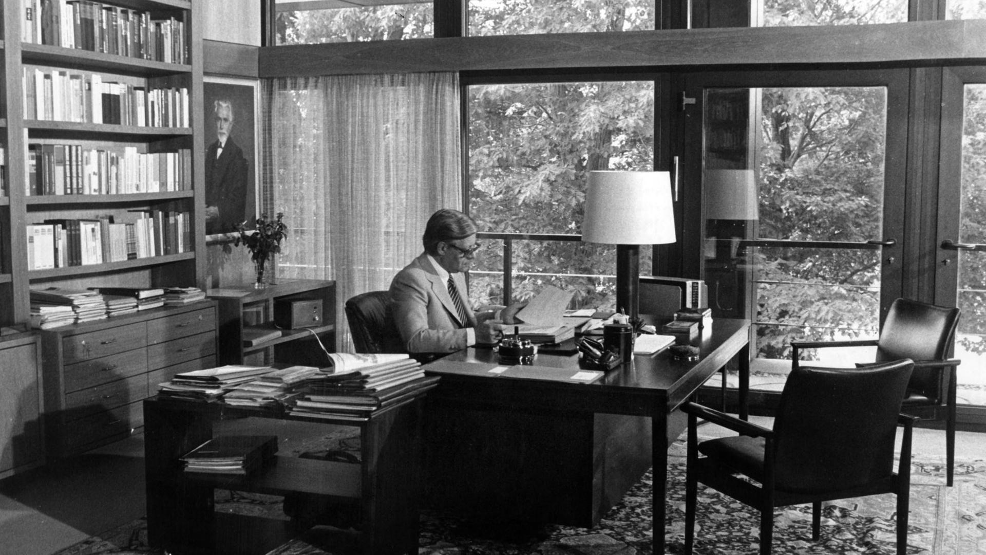 Helmut Schmidt sitzt am Schreibtisch, links hinter ihm eine Bücherwand.