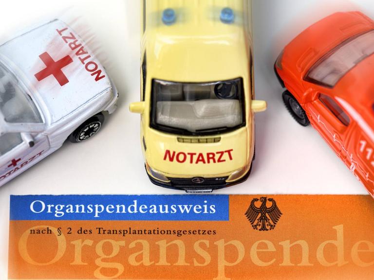 Ein Organspendeausweis, darauf stehen Spielzeugautos: Rettungswagen und Notarzt.