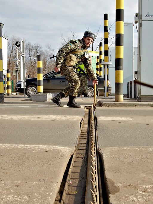 Ein ukrainischer Grenzbeamter errichtet eine Sperre an der russisch-ukrainischen Grenze in der Nähe des Ortes Goptivka.