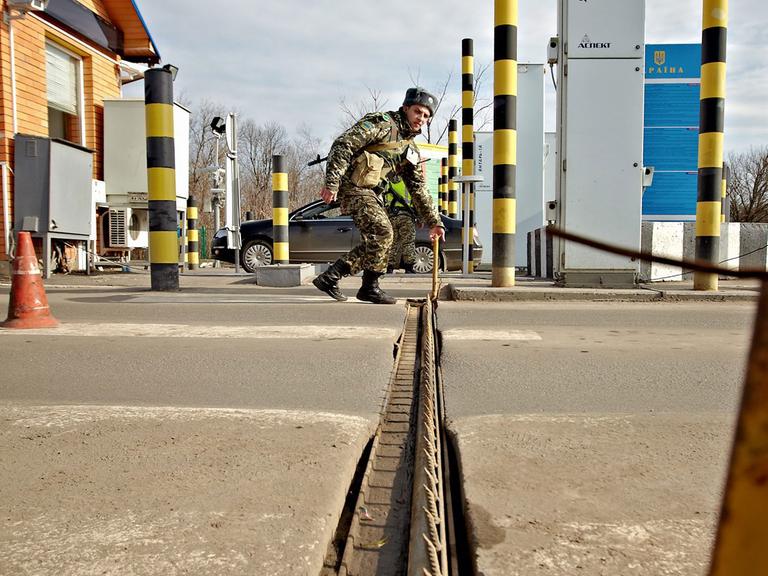 Ein ukrainischer Grenzbeamter errichtet eine Sperre an der russisch-ukrainischen Grenze in der Nähe des Ortes Goptivka.