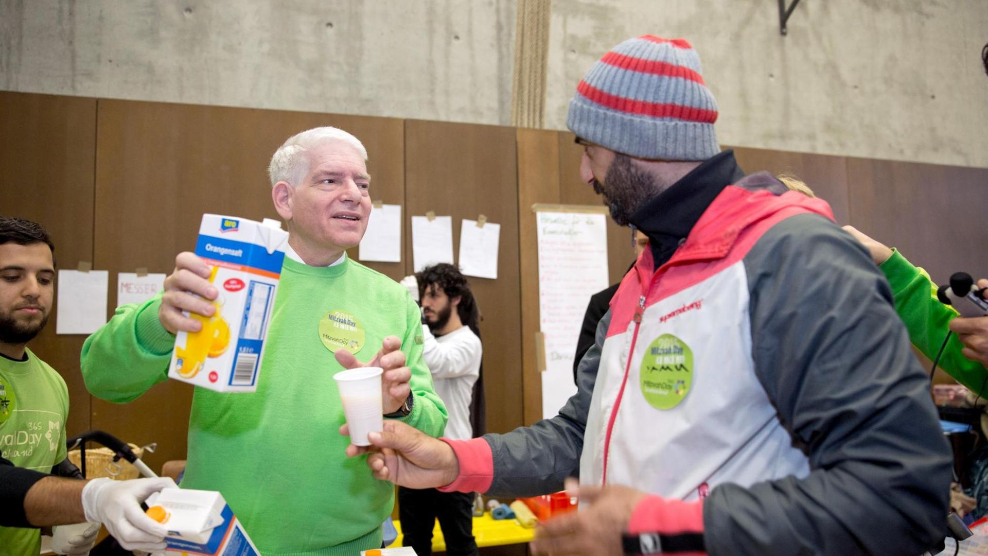Der Präsident des Zentralrats der Juden, Schuster, verteilt im Rahmen des Mitzvah Day Essen an die Bewohner einer Flüchtlingsunterkunft in Berlin.