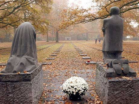 Deutscher Soldatenfriedhof in Vladslo, Belgien, mit der Kollwitz-Skulptur "Trauernde Eltern". Die Figur des Vaters, rechts, blickt auf den 9. Grabstein direkt vor ihm, in den der Name von Kollwitz' Sohn Peter eingraviert ist, der im I. Weltkrieg fiel.
