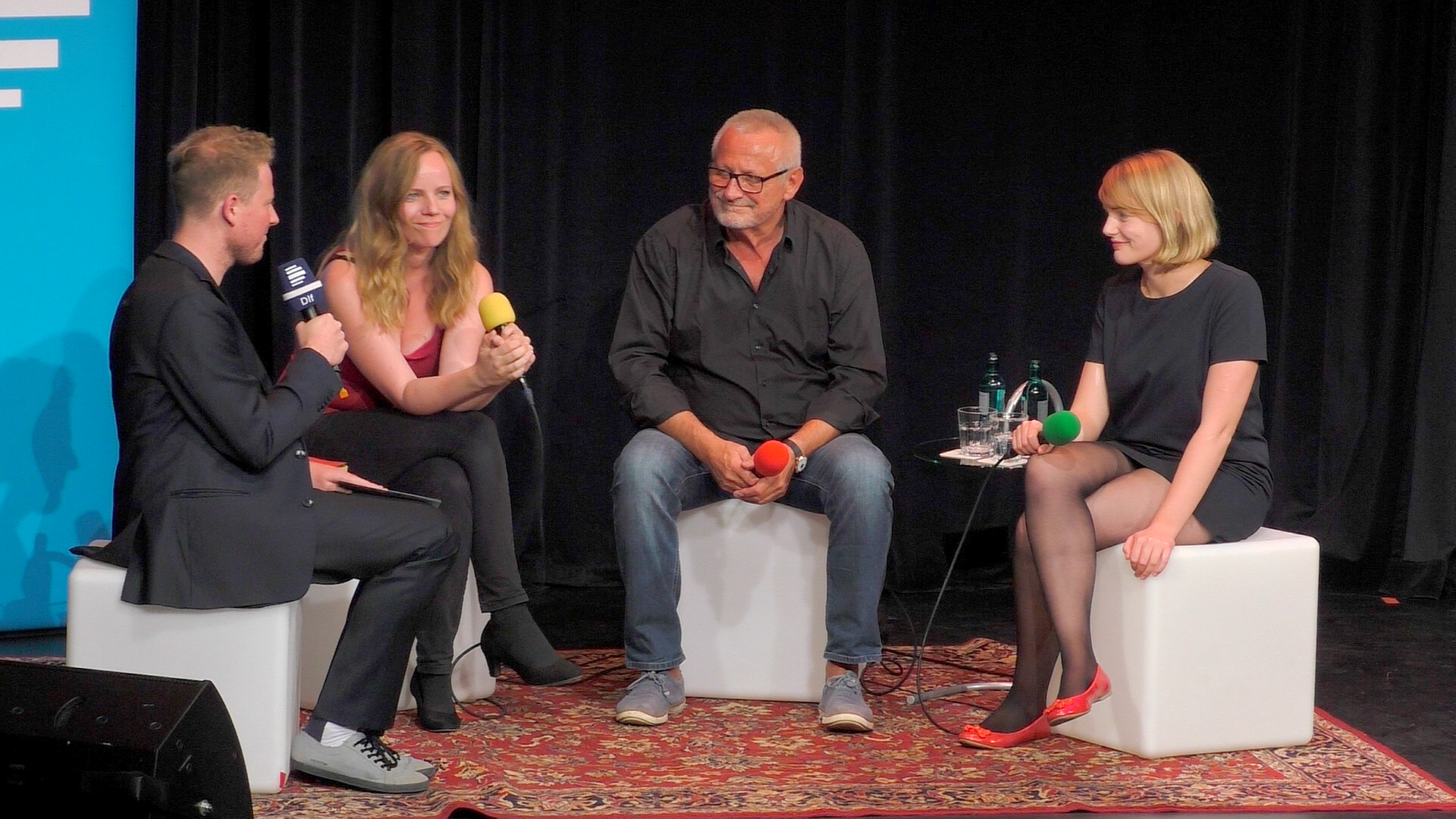 Martin Zingsheim sitzt auf einer Bühne mit Sarah Bosetti, Konstantin Wecker und Ria Schröder