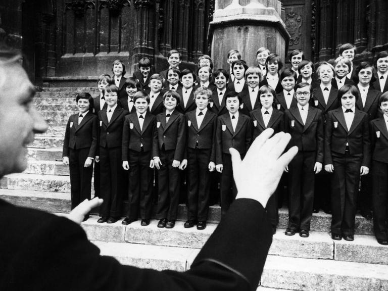 Der Chorleiter Monsignore Georg Ratzinger dirigiert die Domspatzen vor dem Dom in Regensburg am 09.04.1976. Der Regenburger Domchor, "Domspatzen" im Volksmund genannt, beging 1976 mit dem 700-jährigen Jubiläum des Regenburger Doms Sankt Peter sein 1000-jähriges Bestehen. Die Geschichte des Chores geht auf die Anfänge des Bistums Regensburg im achten Jahrhundert zurück. Seit 1964 singt er unter der Leitung von Domkapellmeister Monsignore Georg Ratzinger.