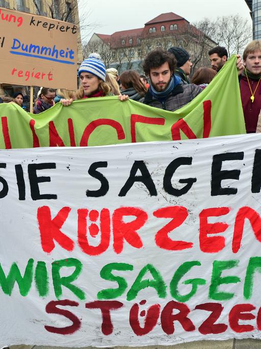 Thüringer Studenten demonstrieren am 11.12.2013 in Erfurt (Thüringen) und fordern mehr Geld für ihre Hochschulen. Sie halten ein Plakat in den Händen auf dem "Sie sagen: Kürzen, Wir sagen: Stürzen" steht.