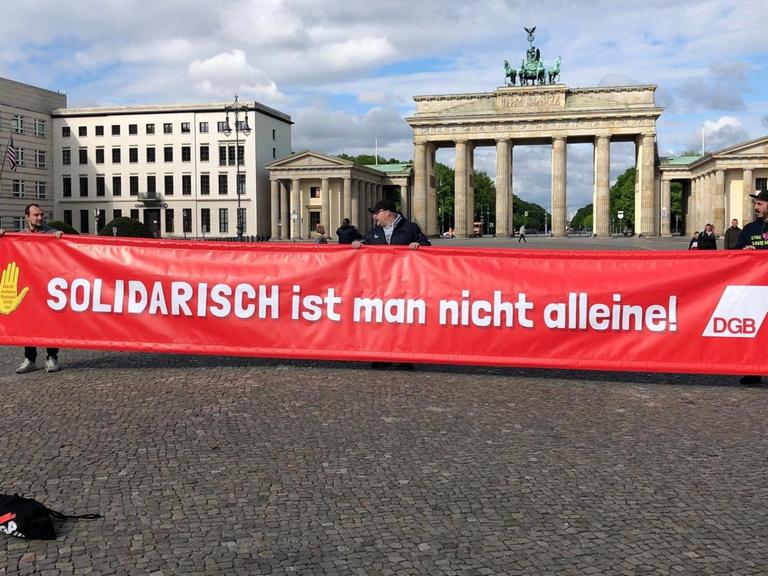Demonstranten tragen ein Banner mit der Aufschrift "Solidarisch ist man nicht alleine" vom Deutschen Gewerkschaftbund vor dem Brandenburger Tor in Berlin