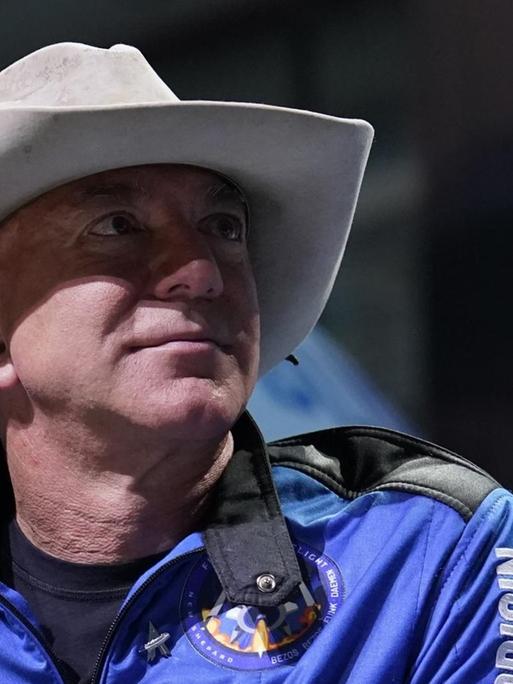 Ein Porträt von Amazon-Gründer Jeff Bezos. Der Unternehmer trägt einen blauen Overall und einen Cowboy-Hut.