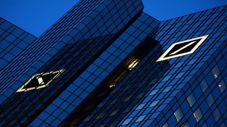 Das Logo der Deutschen Bank leuchtet am 08.01.2014 im Abendlicht auf der Fassade des größten deutschen Geldinstituts in Frankfurt am Main (Hessen). Foto: Arne Dedert/dpa