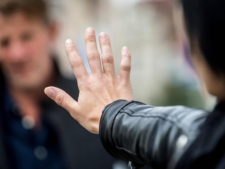 Frau wehrt einen Mann mit einer Handbewegung ab.