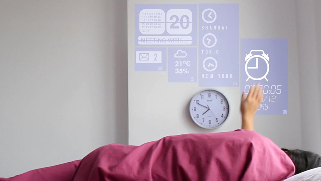 Eine Frau liegt in einem Bett und verändert mit einer Handbewegung das Licht. Die Technik wird in dem Prototyp eines Smart Home in Fuenterrabia in Spanien.