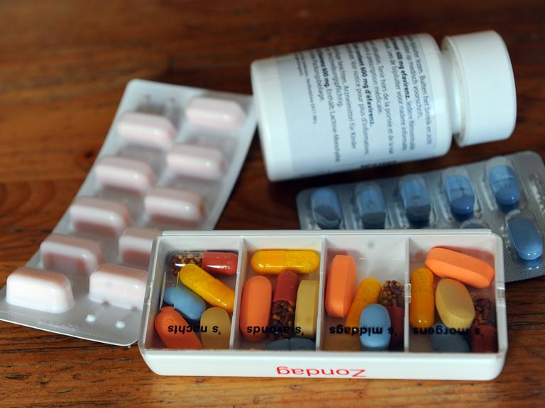 Tabletten eines an AIDS erkrankten Menschen liegen in Tagesrationen und in Blistern sowie einer Dose auf einem Tisch