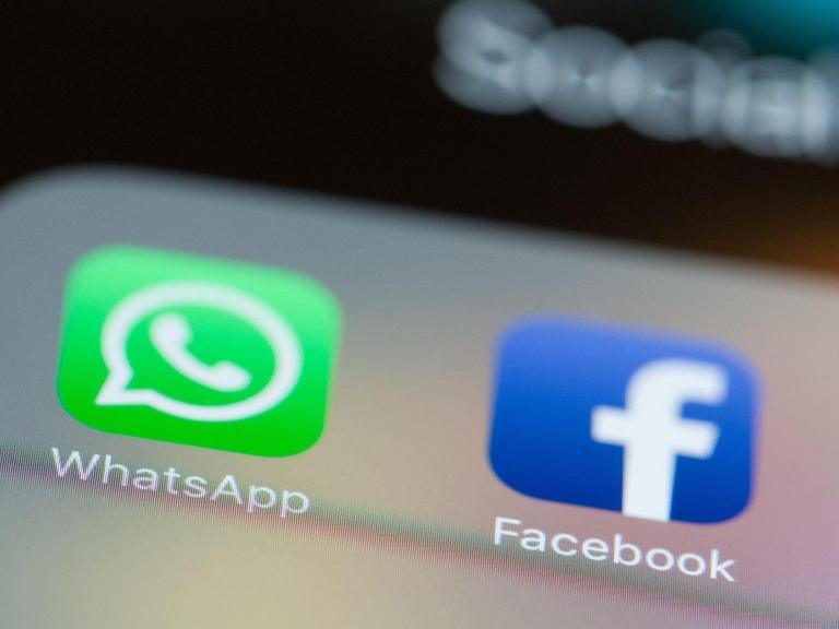 Die Logos von WhatsApp und Facebook leuchten auf einem Smartphone-Bildschirm.