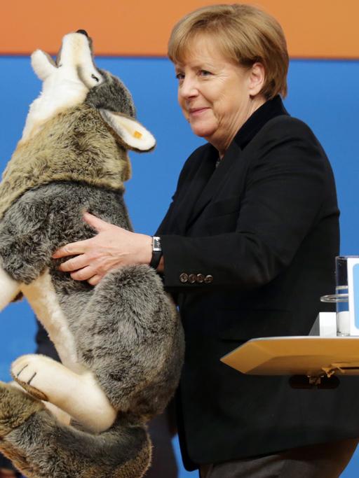 Die CDU-Bundesvorsitzende und Bundeskanzlerin Angela Merkel hält am 14.12.2015 in Karlsruhe beim CDU-Bundesparteitag einen Plüschwolf in der Hand.