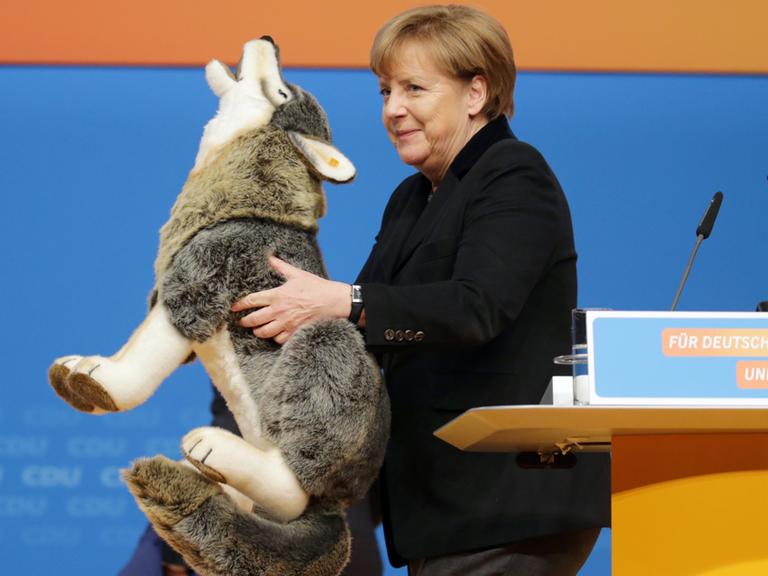 Die CDU-Bundesvorsitzende und Bundeskanzlerin Angela Merkel hält am 14.12.2015 in Karlsruhe beim CDU-Bundesparteitag einen Plüschwolf in der Hand.