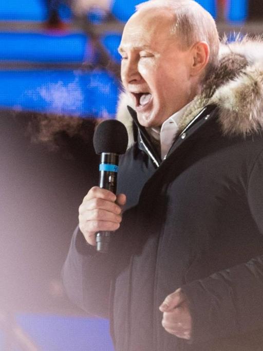 Russlands Präsident spricht auf einer Bühne mit Mikrophon nach gewonnener Wahl zu seinen Anhängern