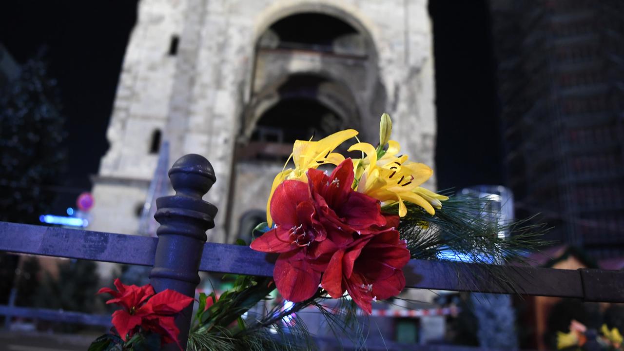 Blumen zum Gedenken an die Opfer stecken an einem Geländer vor dem Weihnachtsmarkt an der Gedächtniskirche in Berlin