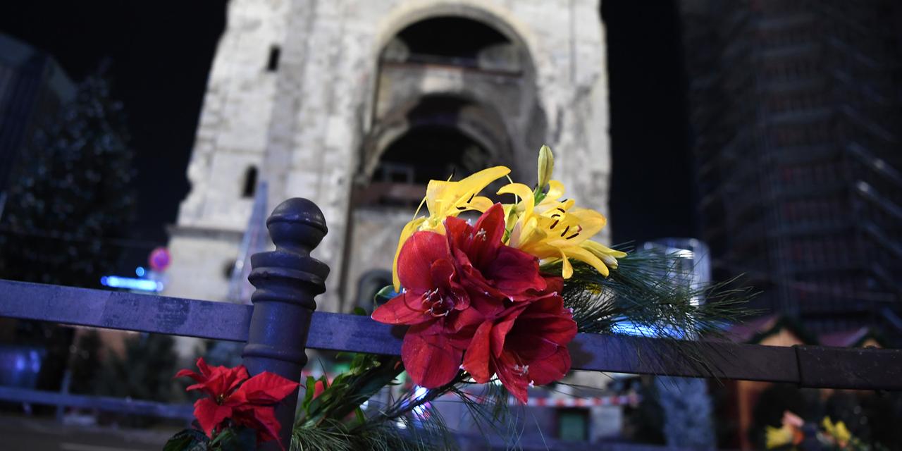 Blumen zum Gedenken an die Opfer stecken an einem Geländer vor dem Weihnachtsmarkt an der Gedächtniskirche in Berlin