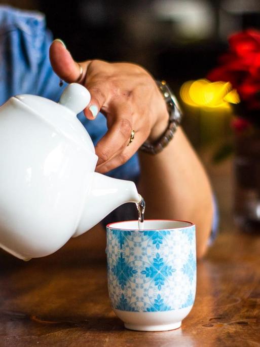 Eine Frau schenkt sich Teewasse in eine Tasse ein.