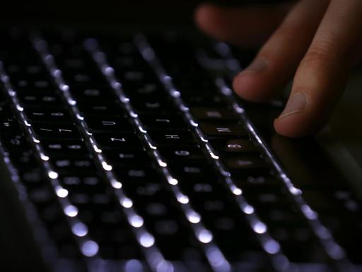 Dunkle Tastatur mit Männerhand