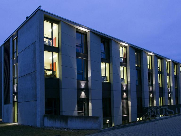 In einem modernen Würfelbau sind viele Fenster erleuchtet.